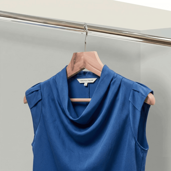 Blue sleeveless top on a hanger against a neutral background