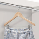 Patterned pants on a wooden hanger against a neutral background