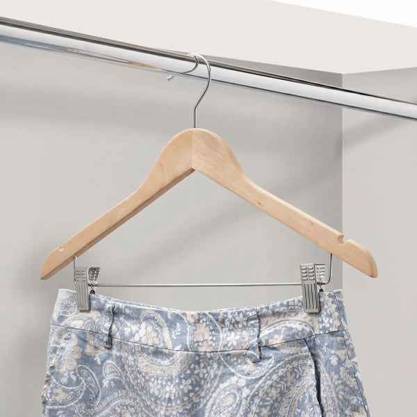 Patterned pants on a wooden hanger against a neutral background