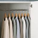 Wooden coat hangers with assorted shirts and knitwear in a modern white wardrobe