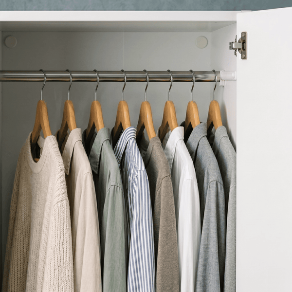 Wooden coat hangers with assorted shirts and knitwear in a modern white wardrobe