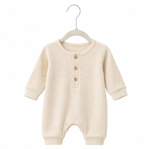 Beige baby romper on a hanger against a white background