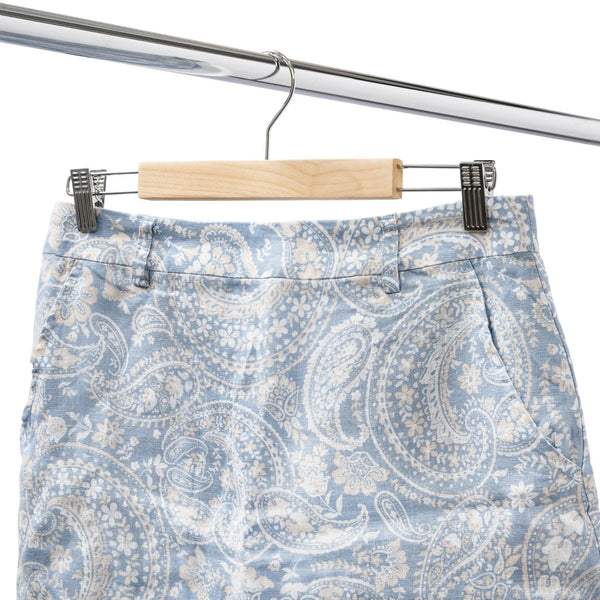 Blue paisley patterned shorts on a hanger against a white background