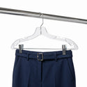 Navy blue pants with a belt on a clear hanger against a white background