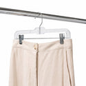 a beige colour trouser is hanging on a clear pant hanger with clips 