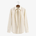 Beige dress shirt on a hanger against a white background