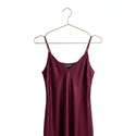 Maroon slip dress on a gold hanger against a white background