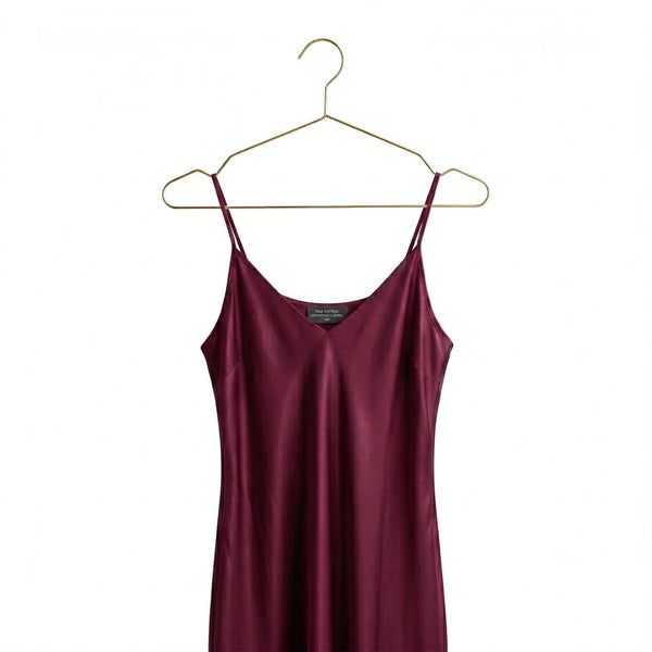 Maroon slip dress on a gold hanger against a white background