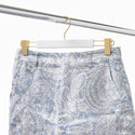 Blue and white paisley patterned shorts on a hanger against a white background