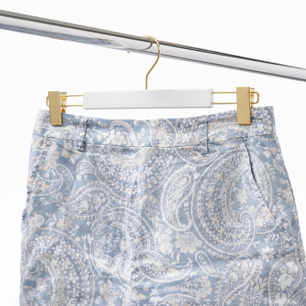 Blue and white paisley patterned shorts on a hanger against a white background