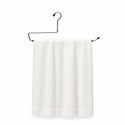 White towel hanging on a black metal towel rack against a white background